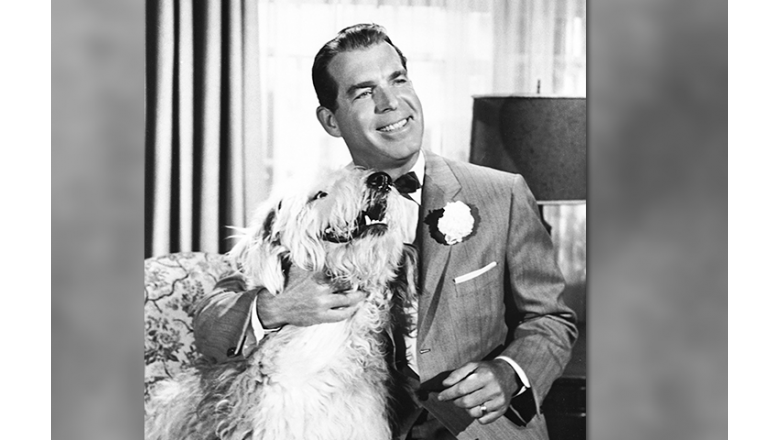photo of actor Fred MacMurray seated holding a large shaggy dog