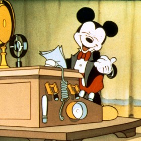 Mickey standing at a podium