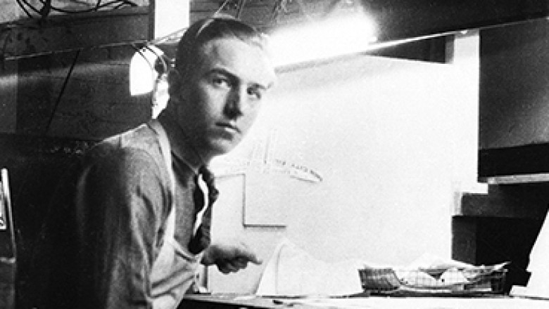 black and white photo of a young Walt Disney at workbench wearing a full-length apron