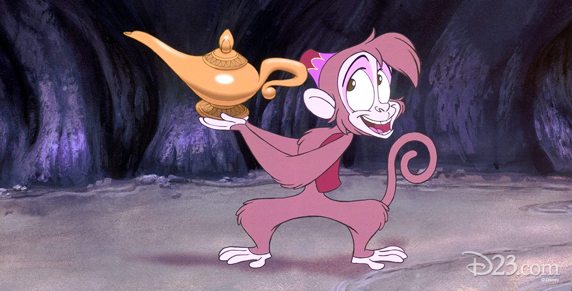 still from animated feature Aladdin featuring Abu the monkey in a cave holding Aladdin's Lamp