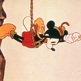 still of Mickey in climber gear dangling from a rope in Alpine Climbers