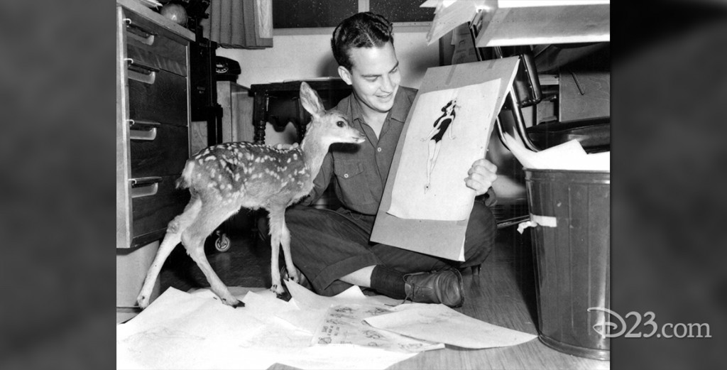 photo of Bill Justice sitting on floor holding a recent sketch in one hand and a live doe in the other