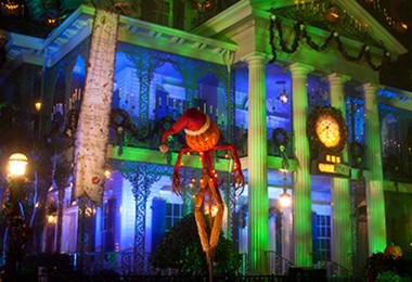 photo of The Haunted Mansion at Disneyland Resort decorated and all lit up for the holidays