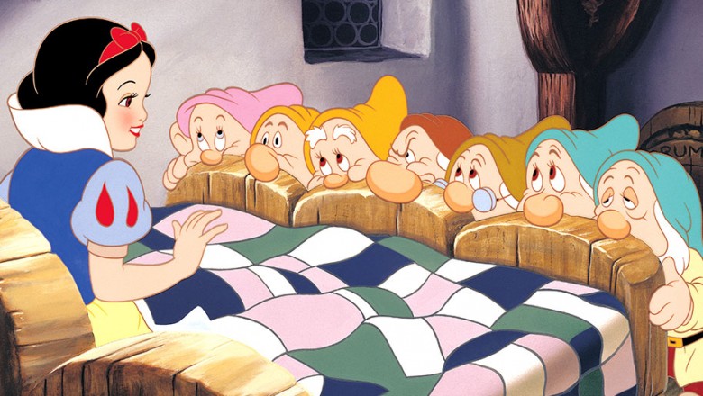 cel from animated classic Snow White and the Seven Dwarfs showing the seven dwarfs all huddled at the foot of Snow White's bed