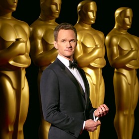 Photo of Neil Patrick Harris standing in front of row of Oscar statues