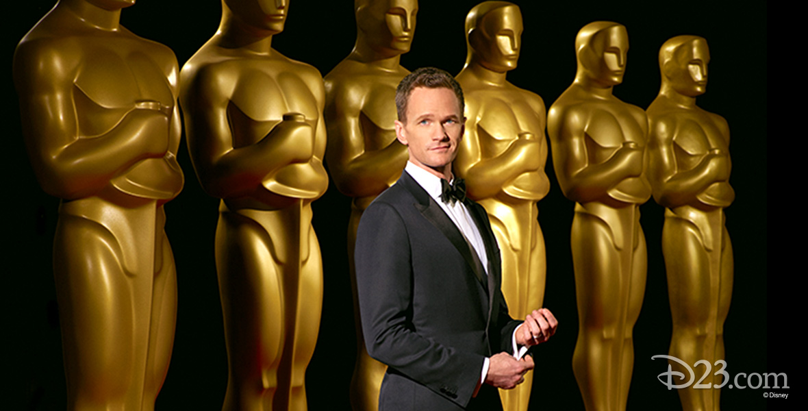 Photo of Neil Patrick Harris standing in front of row of Oscar statues