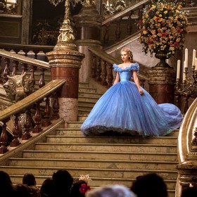 movie still of Cinderella in an elaborate blue dress descending grand stairway