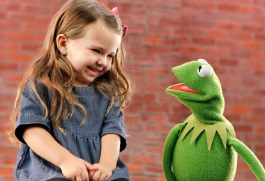 still of little girl laughing as she talks to Kermit the Frog