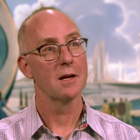 photo of art director Ramsey Avery in front of illustration of Tomorrowland from the movie Tomorrowland