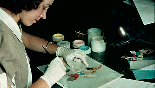 An artist in the Inking and Painting Department adds color to a cel featuring Pinocchio