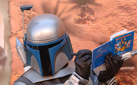 photo of helmeted Star Wars-inspired character signing autograph book