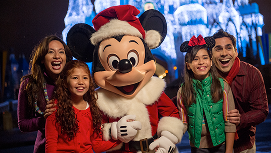 photo of family huddled together around full-size Mickey Mouse character who is dressed like Santa Claus