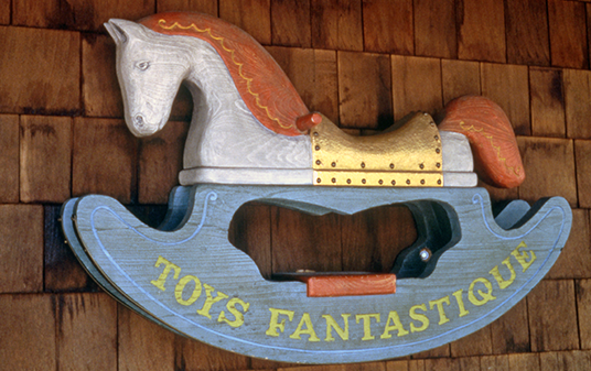 photo of fanciful carved wooden sign in the shape of a rocking horse with painted text Toys Fantastique