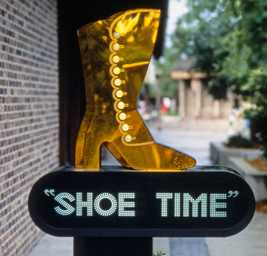 photo of sign for Shoe Time shop featuring golden women's high-heeled boot