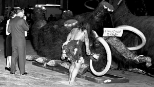 photo of giant Mammoth legs in the air, marked with a sign Christmas Turkey and a life-size cave man figure standing near it