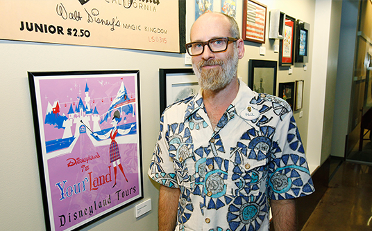 photo of Paul Rudish, Creator and Executive Producer, Mickey Mouse cartoon shorts, next to illustrated poster for early Disneyland Tours