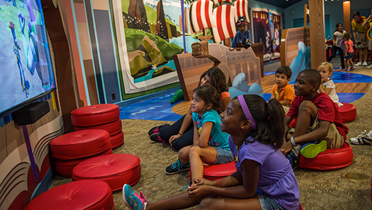 photo of children sitting on floor in playroom watching large-screen TV at Disney’s Polynesian Village Resort