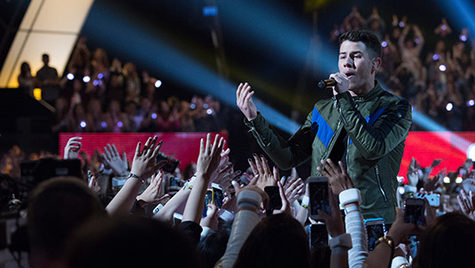 photo of Nick Jonas singing to large crowd