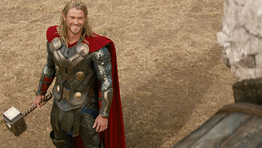 movie still of Thor smiling holding his hammer