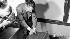 photo of Walt Disney examinig his scratched initials in his childhood school desk in Marceline, Missouri