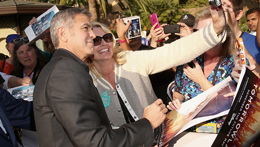 George Clooney stops for photos with some D23 Members on the blue carpet.