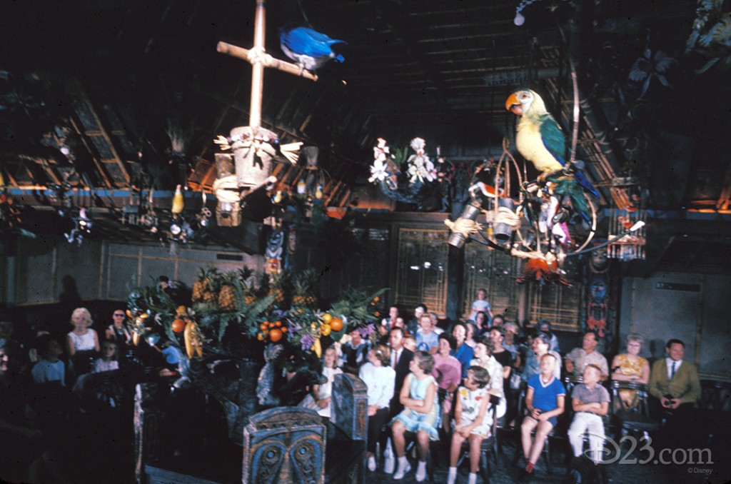 photo of enchanted children and parents seated in interior of the enchanted tiki room looking up at perched birds