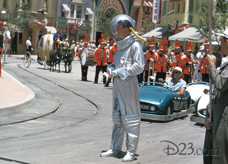 A man dressed as an astronaut in front of Bub Gurr in an Autopia car