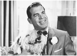 photo of actor Fred MacMurray seated holding a large shaggy dog