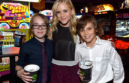 photo of actors Ed Oxenbould, Sidney Fullmer, and Lincoln Melcher posing amid game arcade