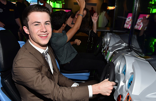 photo of actor Dylan Minnette playing driving game at arcade