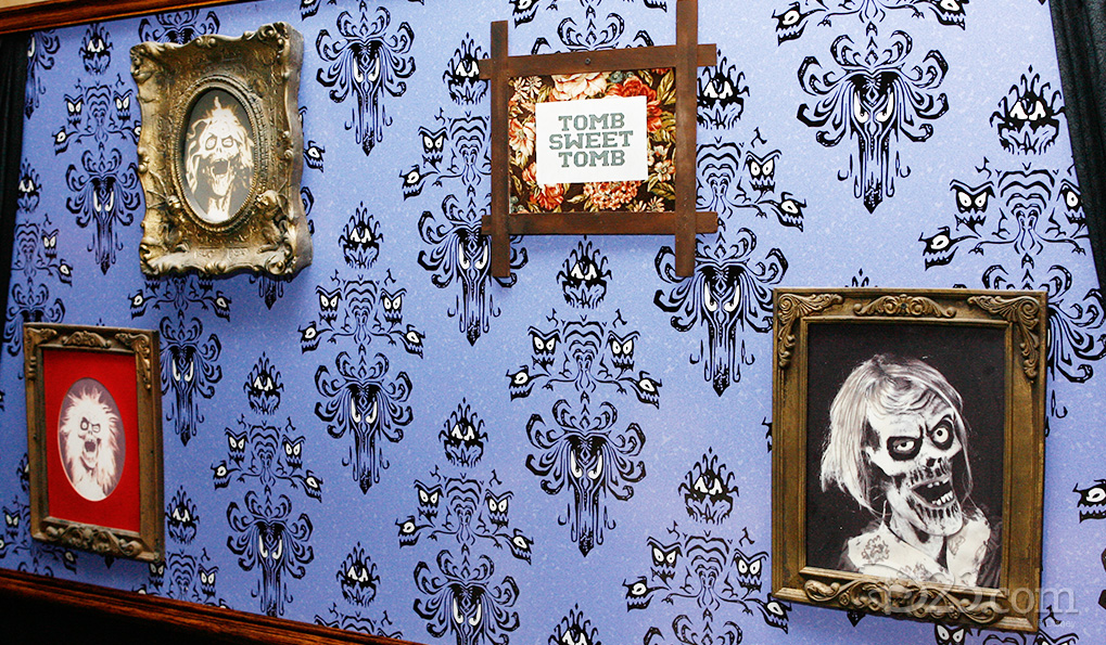 photo of reproduction eyeball-wallpaper with framed pictures of ghouls and skeletons and one stating Home Sweet Tomb