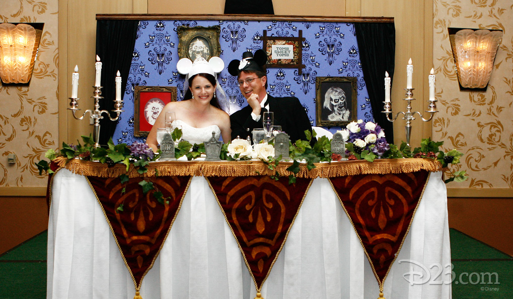 photo of Jason Thompson and his new bride Melissa seated at head table at reception wearing mickey mouse ear caps