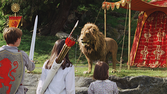 scene from the movie The Chronicles of Narnia: The Lion, the Witch and the Wardrobe in which three children armed with sword and bow and arrow confront a mighty lion