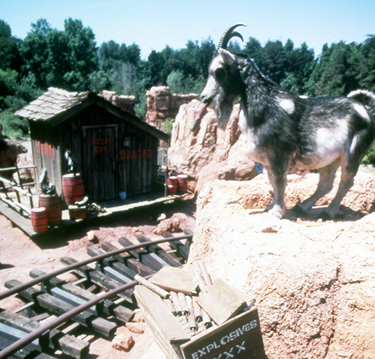 photo of Audio-Animatronic mountain goat atop a cliff overlooking tracks and utility shed of Big Thunder Railroad attraction at Disneyland