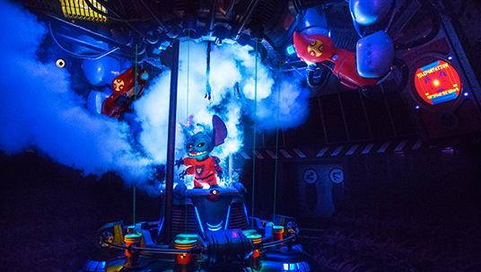 photo of gremlin-like creature surrounded by plumes of steam and brightly colored machinery