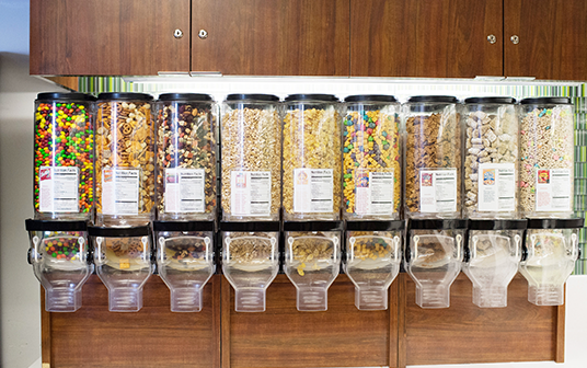photo of line up of nine clear plastic dispenser jars containing cereal and other snacks at a kitchen at TVA