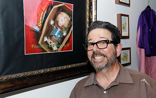 photo of Rob LaDuca standing next to his framed illustration of Gruffy the zombie Gummy Bear