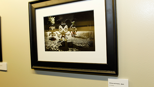 framed photo by Eric Coleman of three small figurines representing zombie versions of Donald Duck, Mickey Mouse, and Goofy creeping toward camera 