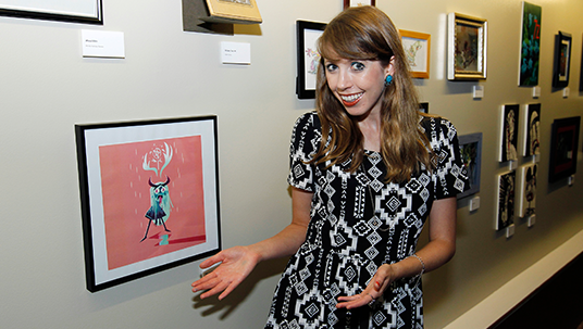 photo of Daron Nefcy, creator of Star Vs. the Forces of Evil, with a framed illustration of 