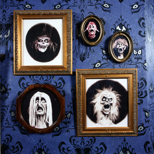 photo of several framed portraits of ghouls on wall featuring eyes designed by "Museum of the Weird" creator Rolly Crump and Claude Coats