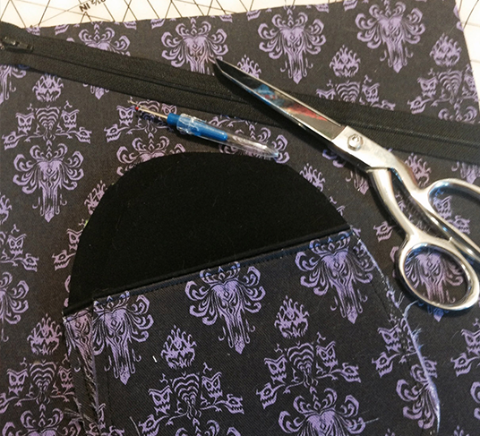 close up photo of shirt pocket detail being sewn using black and purple Haunted Mansion patterned fabric