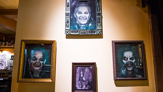 photo of wall on which are hung four framed illustrations of ghouls and creepy looking people