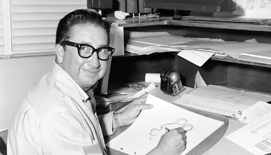 black and white photo of Francis Xavier Atencio, also known as X Atencio, is a former animator and Imagineer for The Walt Disney Company, seated sketching Winnie the Pooh