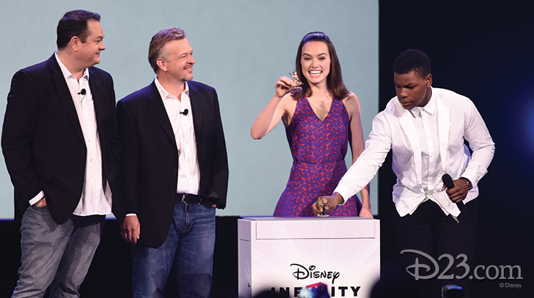 photo of cast of Star Wars The Force Awakens presenting play set action figures on stage, including actors John Boyega and Daisy Ridley plus John Blackburn, senior vice president and general manager of Disney Infinity, and John Vignocchi, vice president of production