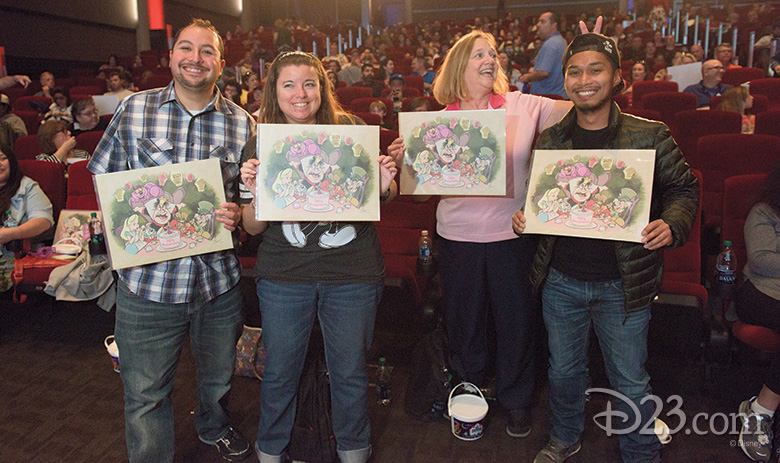D23 Gold Members holding a commemorative gift for Alice in Wonderland