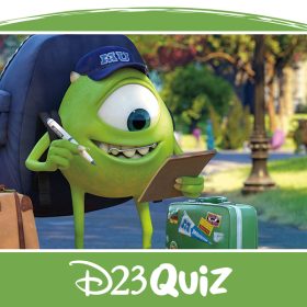 Mike Wazowski, a green, one-eyed monster from Monsters University, is looking at his check list in one hand and has a pen in his other hand while standing on a college campus walk path with green grass on either side of the path. He is wearing a dark blue hat that has "MU" written on the front of it while wearing a dark blue backpack with a tan suitcase and a green suitcase, both featuring stickers, on either side of him.