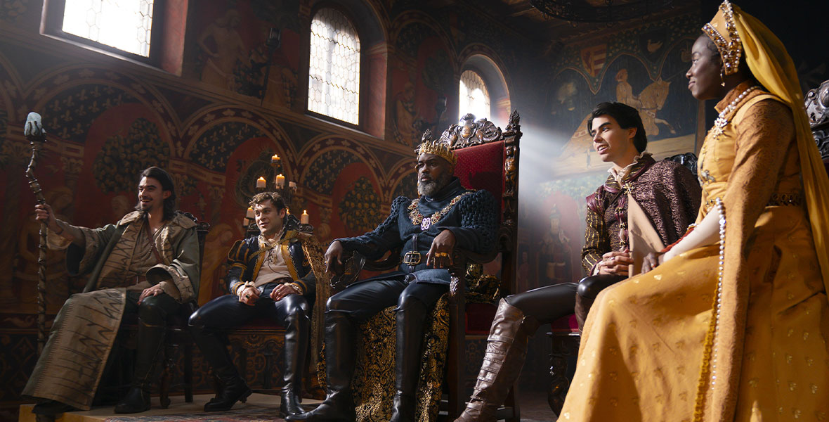 In the Disney+ show The Quest, four men and one women are seated in medieval attire.