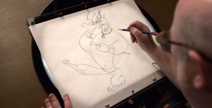 An artist draws Genie with pencil on see-through paper.