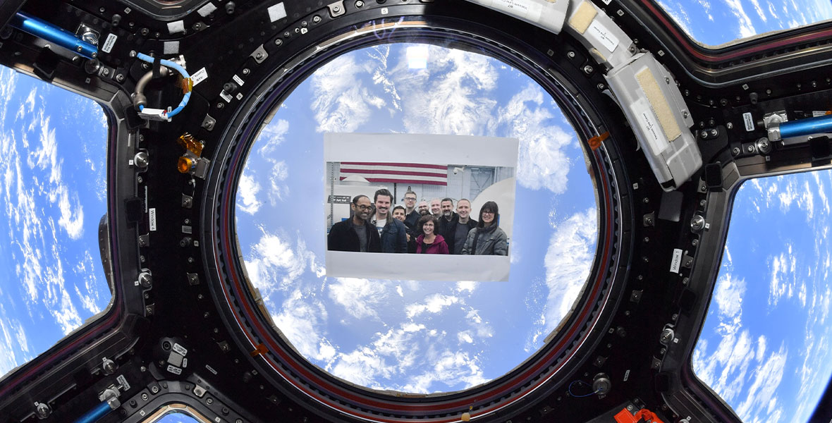 A photograph of the Lightyear filmmakers is placed on a window of the International Space Station with planet earth in clear view behind it.