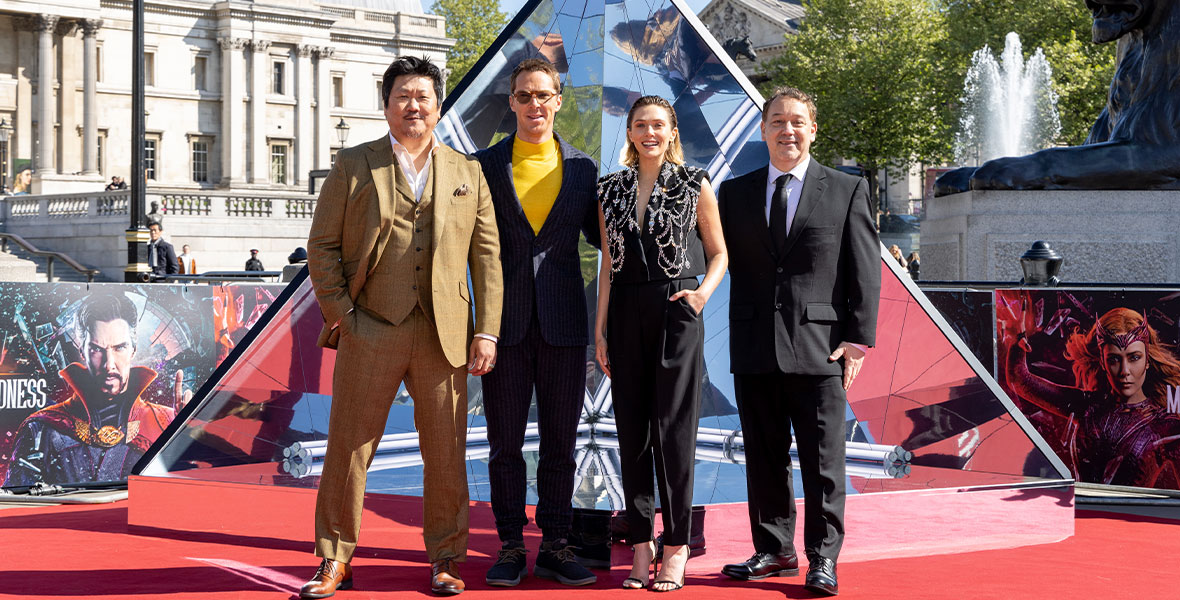 Benedict Cumberbatch, Elizabeth Olsen, and Benedict Wong stand next to each other at a red carpet premiere in Berlin of Doctor Strange in the Multiverse of Madness.